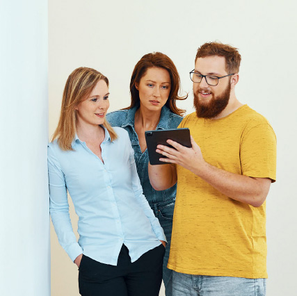Drei Mitarbeiter von BITS stehen und schauen gemeinsam in ein Tablet